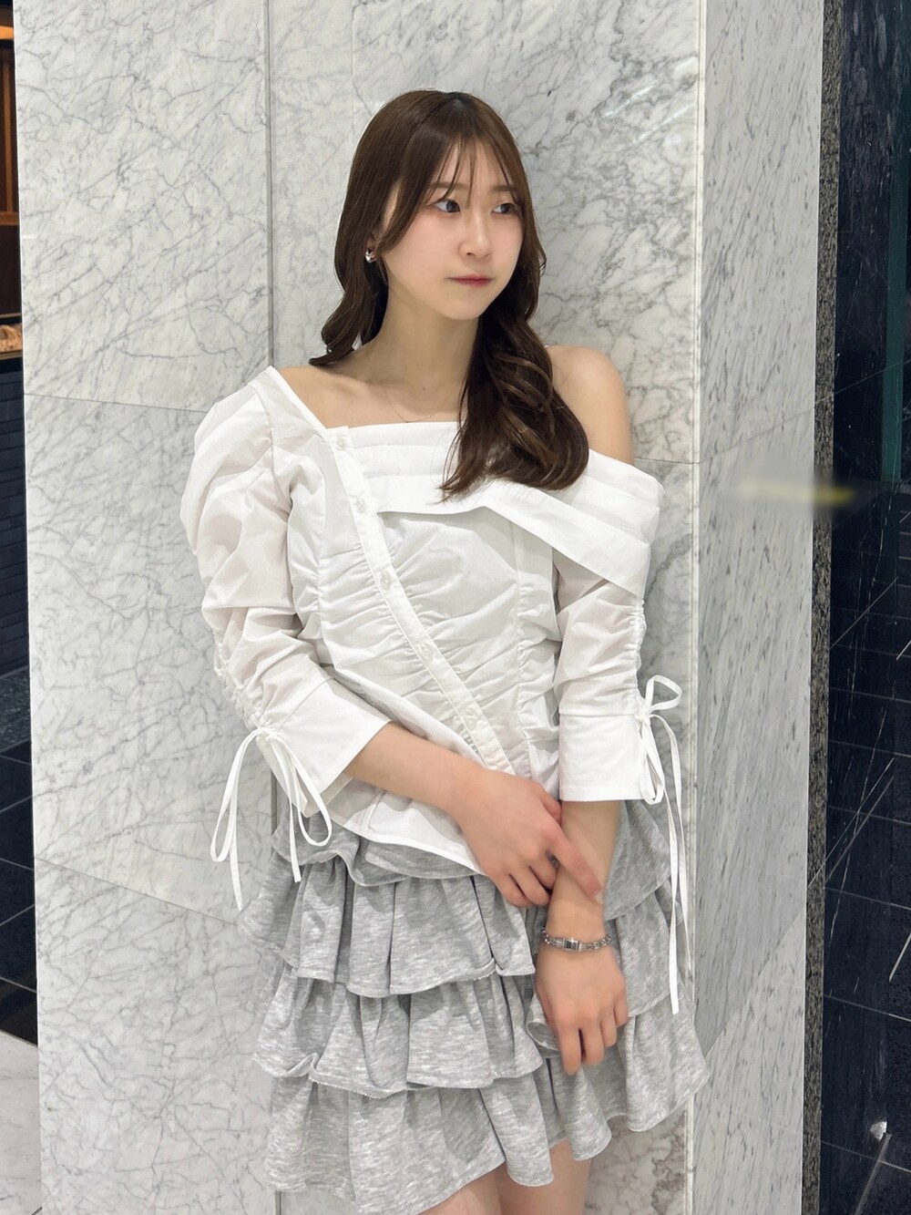 グレー系のスカート、ブルー系のハンドバッグ、ベージュ系のブーツを着用したレディースの春コーディネートの7枚目の写真