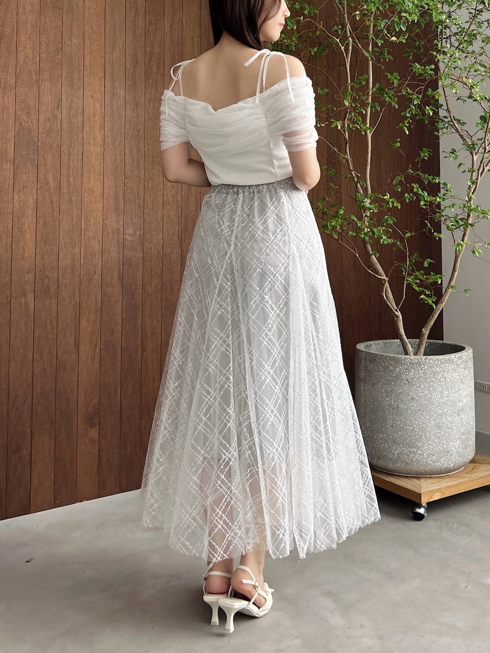 グレー系のスカート、ホワイト系のパンプス、ブラウン系のショルダーバッグを着用したレディースの夏コーディネートの6枚目の写真