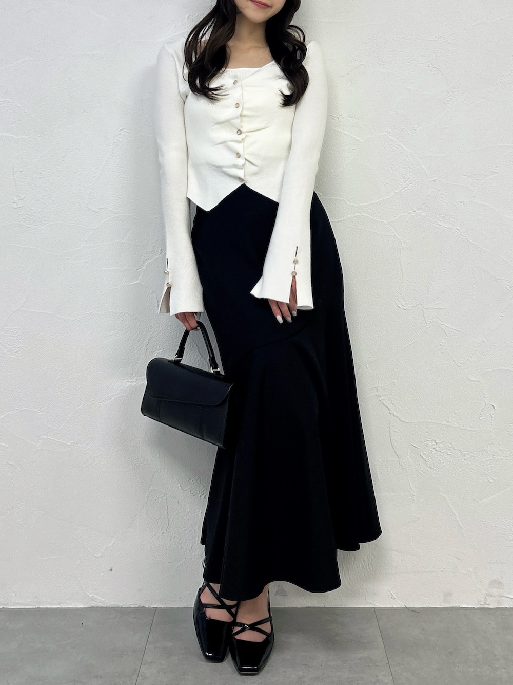 ホワイト系のニット/セーター、ブラック系のスカート、ブラック系のサンダルを着用したレディースの春コーディネートの3枚目の写真