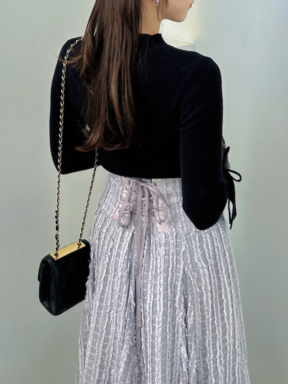 ブラック系のニット/セーター、グレー系のスカート、ブラック系のパンプスを着用したレディースの秋コーディネートの9枚目の写真