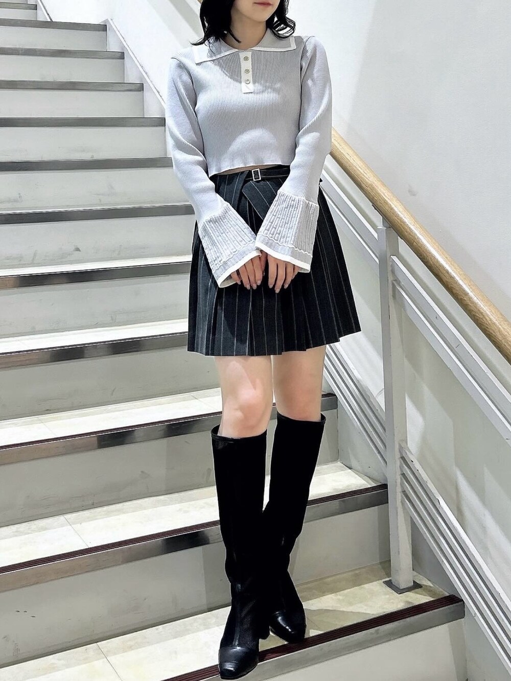 グレー系のニット/セーター、グレー系のスカート、ブラック系のブーツを着用したレディースの冬コーディネートの3枚目の写真