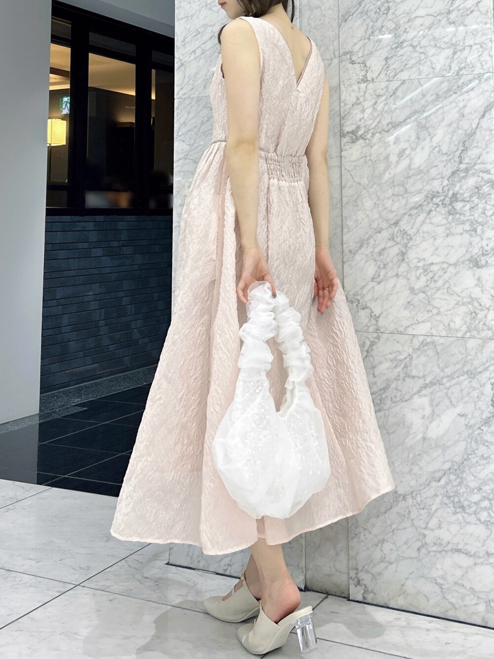 ホワイト系のパンプス、ホワイト系のハンドバッグ、ピンク系のドレスを着用したレディースの夏コーディネートの4枚目の写真