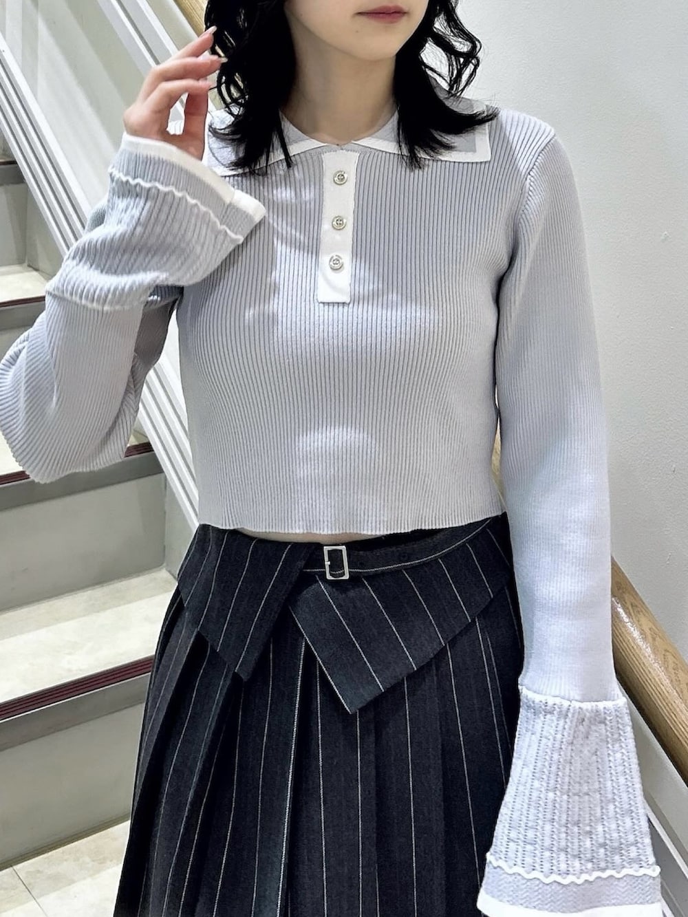 グレー系のニット/セーター、グレー系のスカート、ブラック系のブーツを着用したレディースの冬コーディネートの6枚目の写真