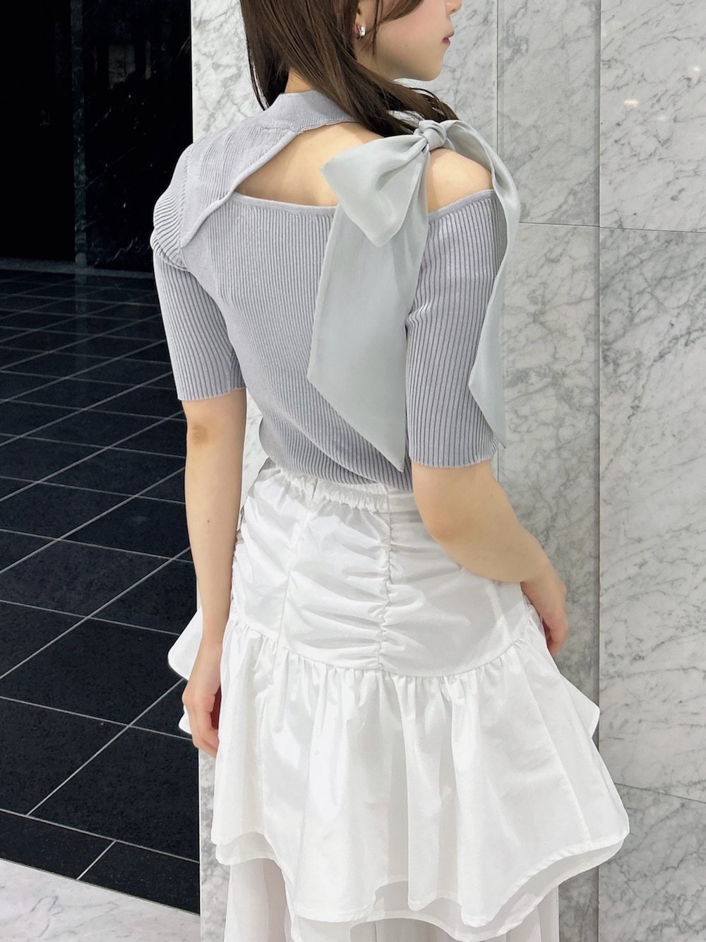 グレー系のニット/セーター、ホワイト系のスカート、ホワイト系のブーツを着用したレディースの春コーディネートの9枚目の写真