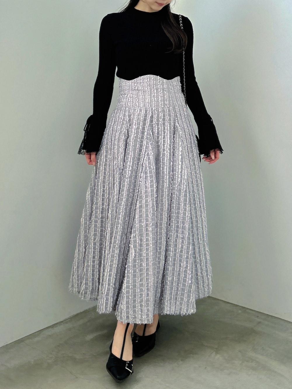 ブラック系のニット/セーター、グレー系のスカート、ブラック系のパンプスを着用したレディースの秋コーディネートの3枚目の写真