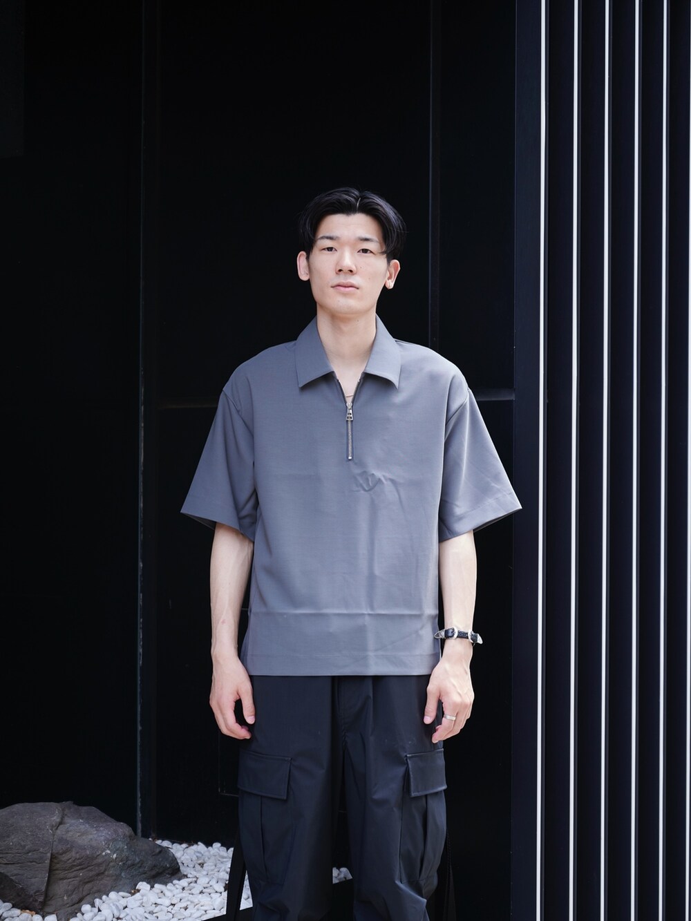 グレー系のポロシャツ、ブラック系のその他パンツ、ホワイト系のスニーカーを着用したメンズの夏コーディネートの4枚目の写真