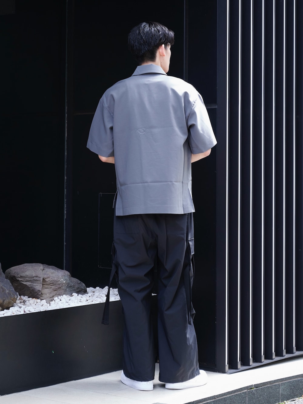 グレー系のポロシャツ、ブラック系のその他パンツ、ホワイト系のスニーカーを着用したメンズの夏コーディネートの3枚目の写真