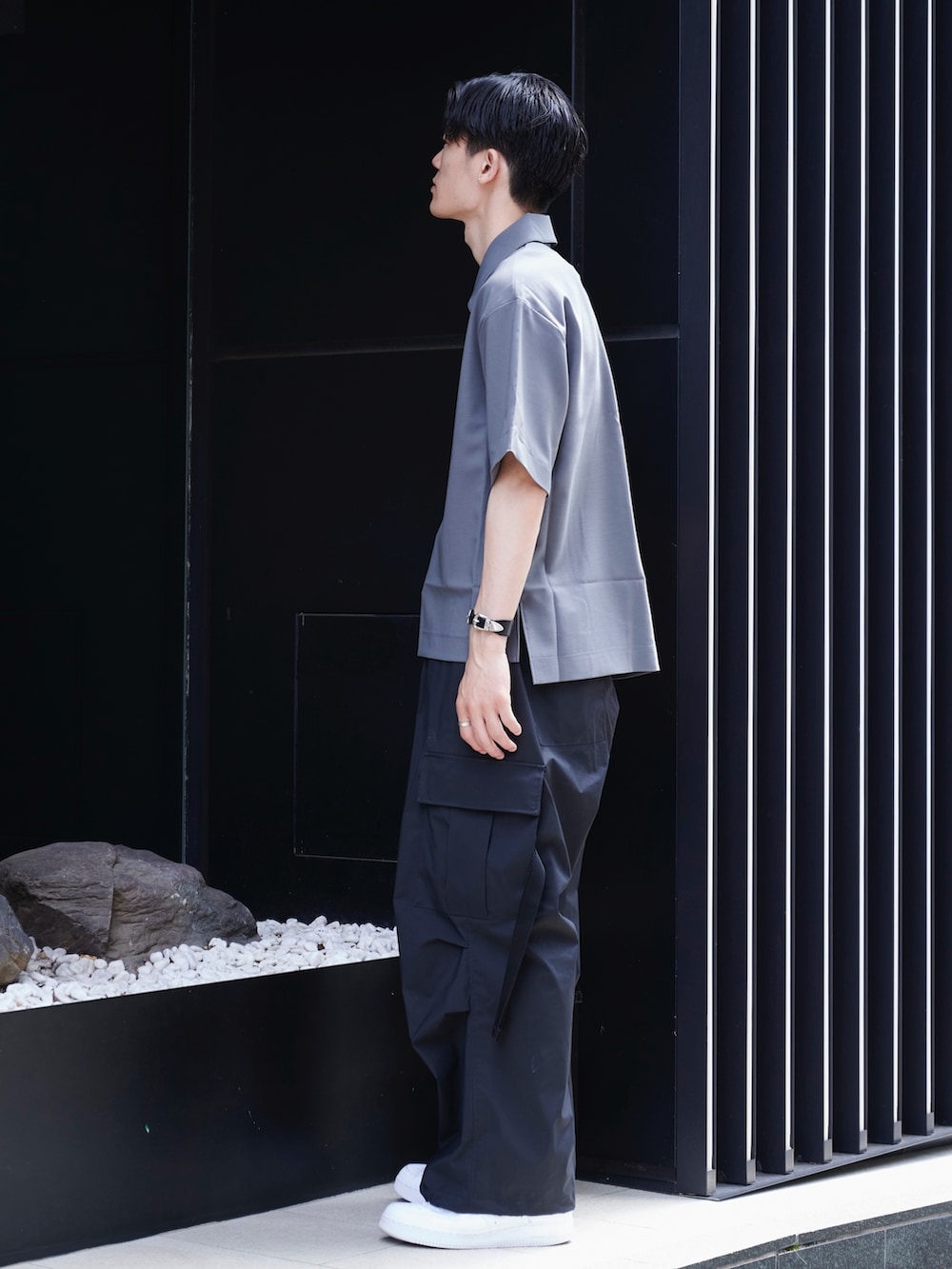 グレー系のポロシャツ、ブラック系のその他パンツ、ホワイト系のスニーカーを着用したメンズの夏コーディネートの2枚目の写真