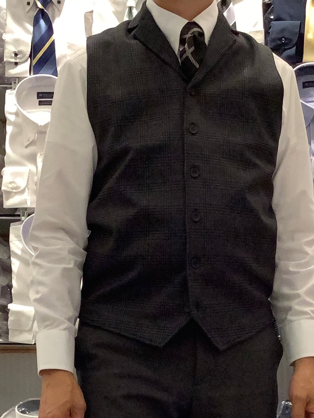 ホワイト系のビジネスシャツ、ブルー系のベストを着用したメンズの秋コーディネートの2枚目の写真