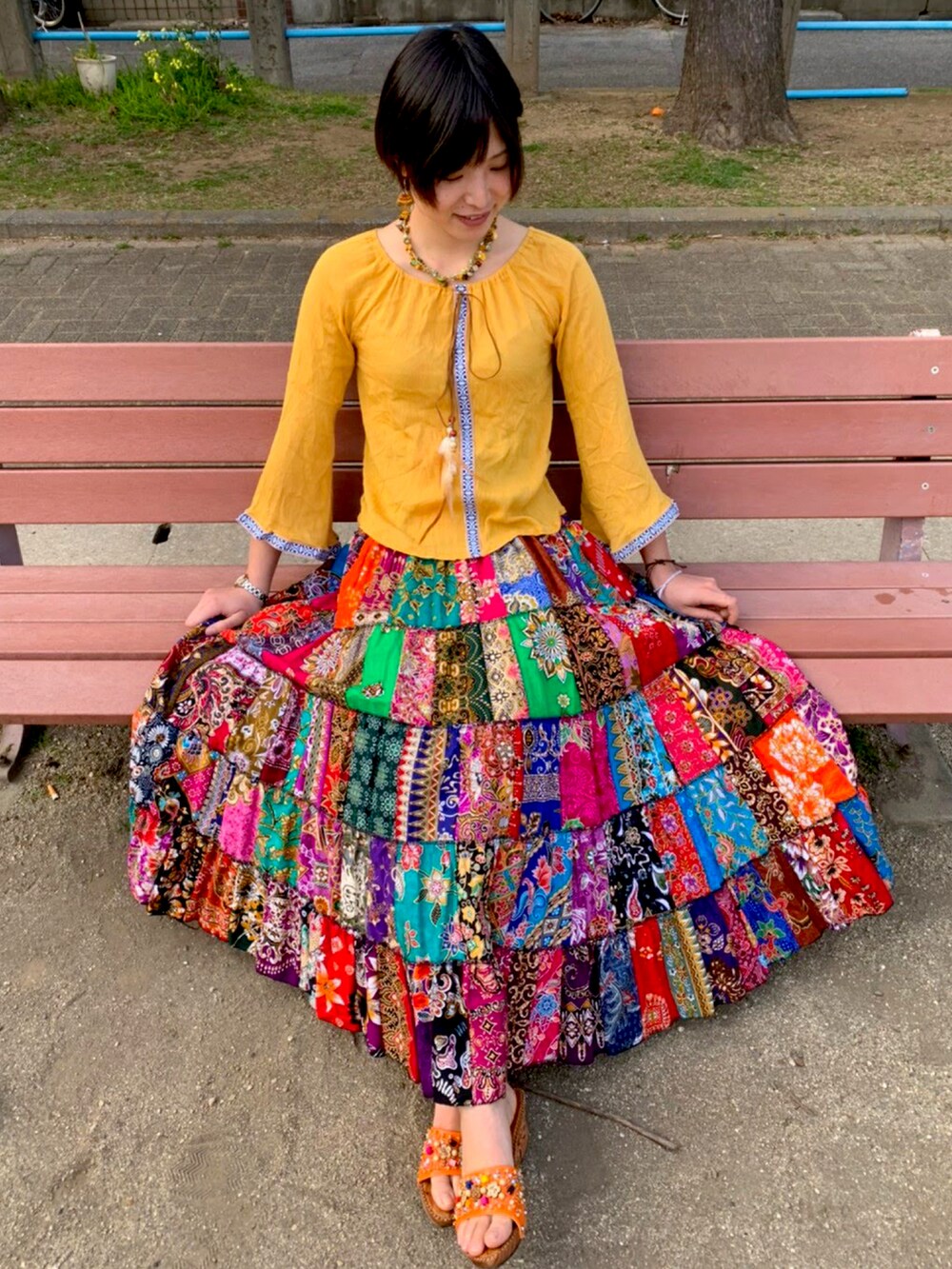 イエロー系のトップス、その他のスカート、オレンジ系のサンダルを着用したレディースの秋コーディネートの2枚目の写真