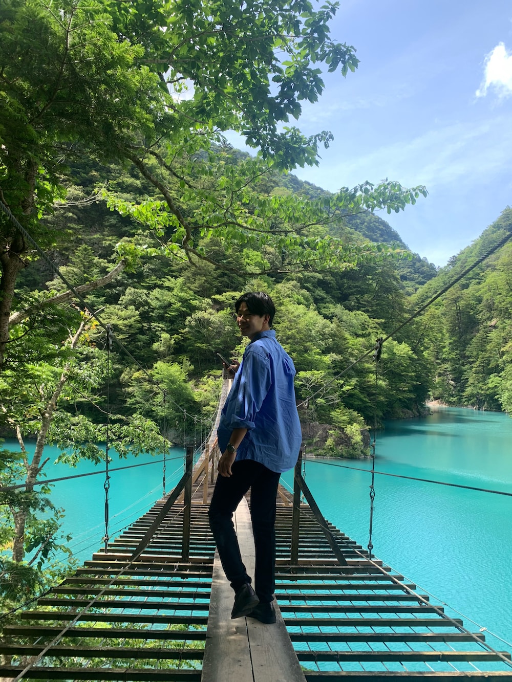 ブラウン系のローファー、ブラック系のスラックス、ブルー系のシャツ/ブラウスを着用したメンズの夏コーディネートの2枚目の写真