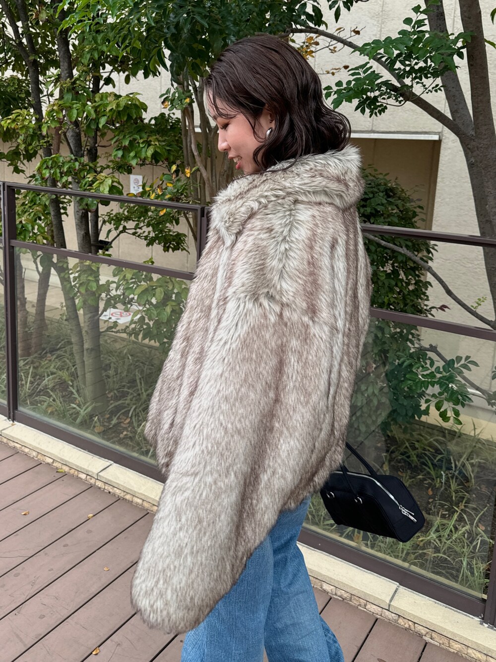 ベージュ系のその他アウター、ブルー系のデニムパンツ、ブラック系のハンドバッグを着用したレディースの秋コーディネートの9枚目の写真