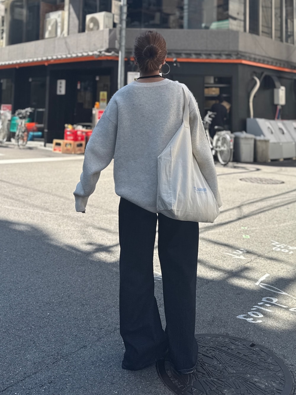 ブルー系のデニムパンツ、ホワイト系のニット/セーター、ホワイト系のトートバッグを着用したレディースの夏コーディネートの6枚目の写真