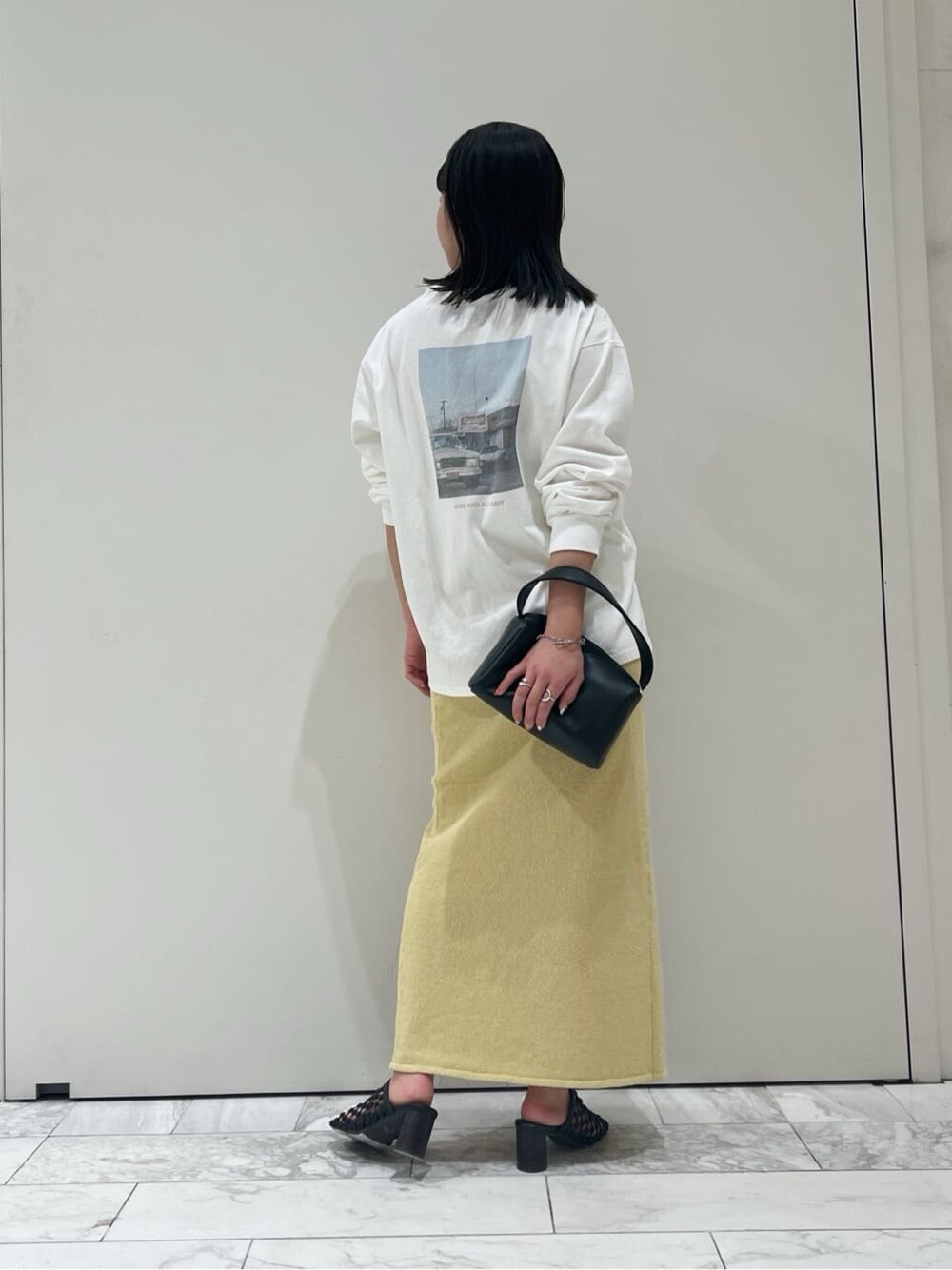 ブラック系のハンドバッグ、イエロー系のスカート、ホワイト系のTシャツ/カットソーを着用したレディースの春コーディネートの4枚目の写真