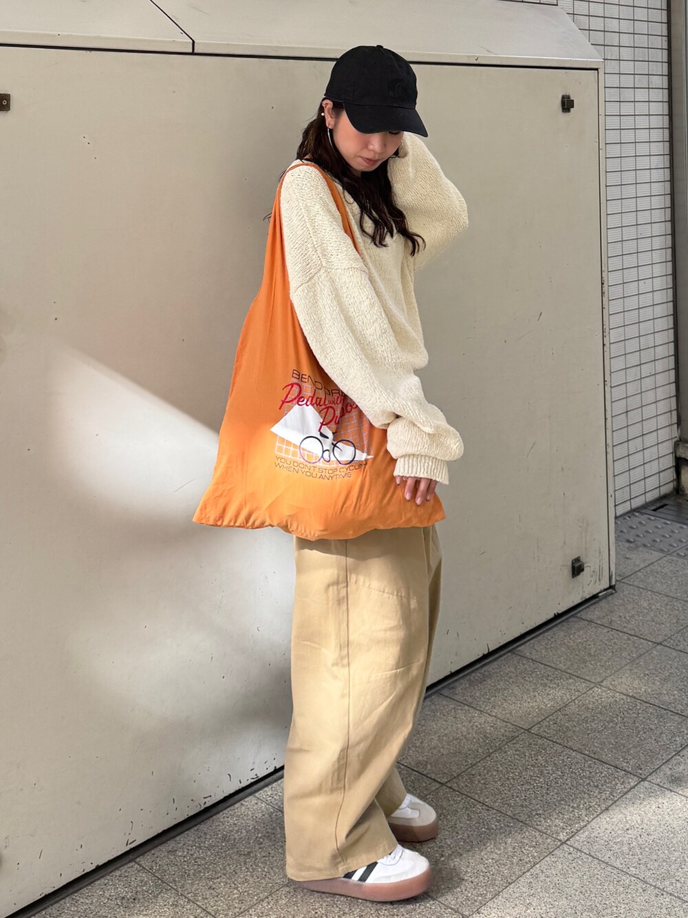 ベージュ系のチノパンツ、ホワイト系のニット/セーター、オレンジ系のエコバッグ/サブバッグを着用したレディースの冬コーディネートの4枚目の写真