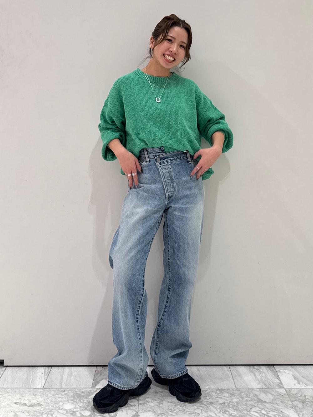 ブルー系のデニムパンツ、グリーン系のニット/セーター、シルバー系のネックレスを着用したレディースの冬コーディネートの2枚目の写真