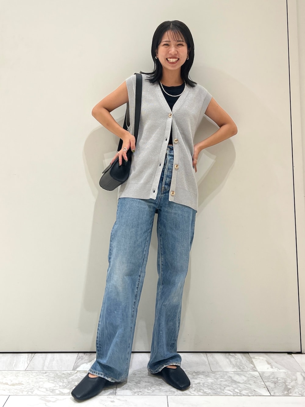 ブルー系のデニムパンツ、ブラック系のショルダーバッグ、シルバー系のベストを着用したレディースの夏コーディネートの6枚目の写真