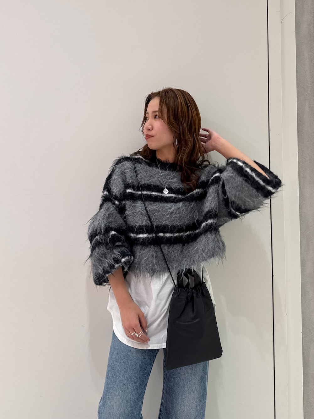 ブラック系のニット/セーター、ホワイト系のTシャツ/カットソー、ブルー系のデニムパンツを着用したレディースの冬コーディネートの9枚目の写真