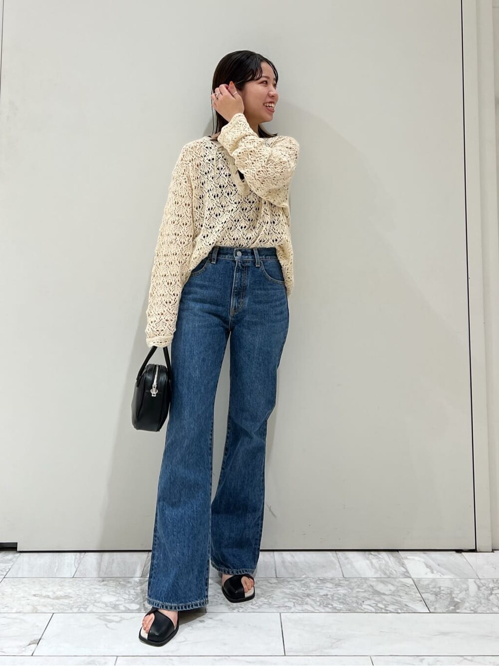 ブラック系のサンダル、ブラック系のハンドバッグ、ブルー系のデニムパンツを着用したレディースの春コーディネートの2枚目の写真