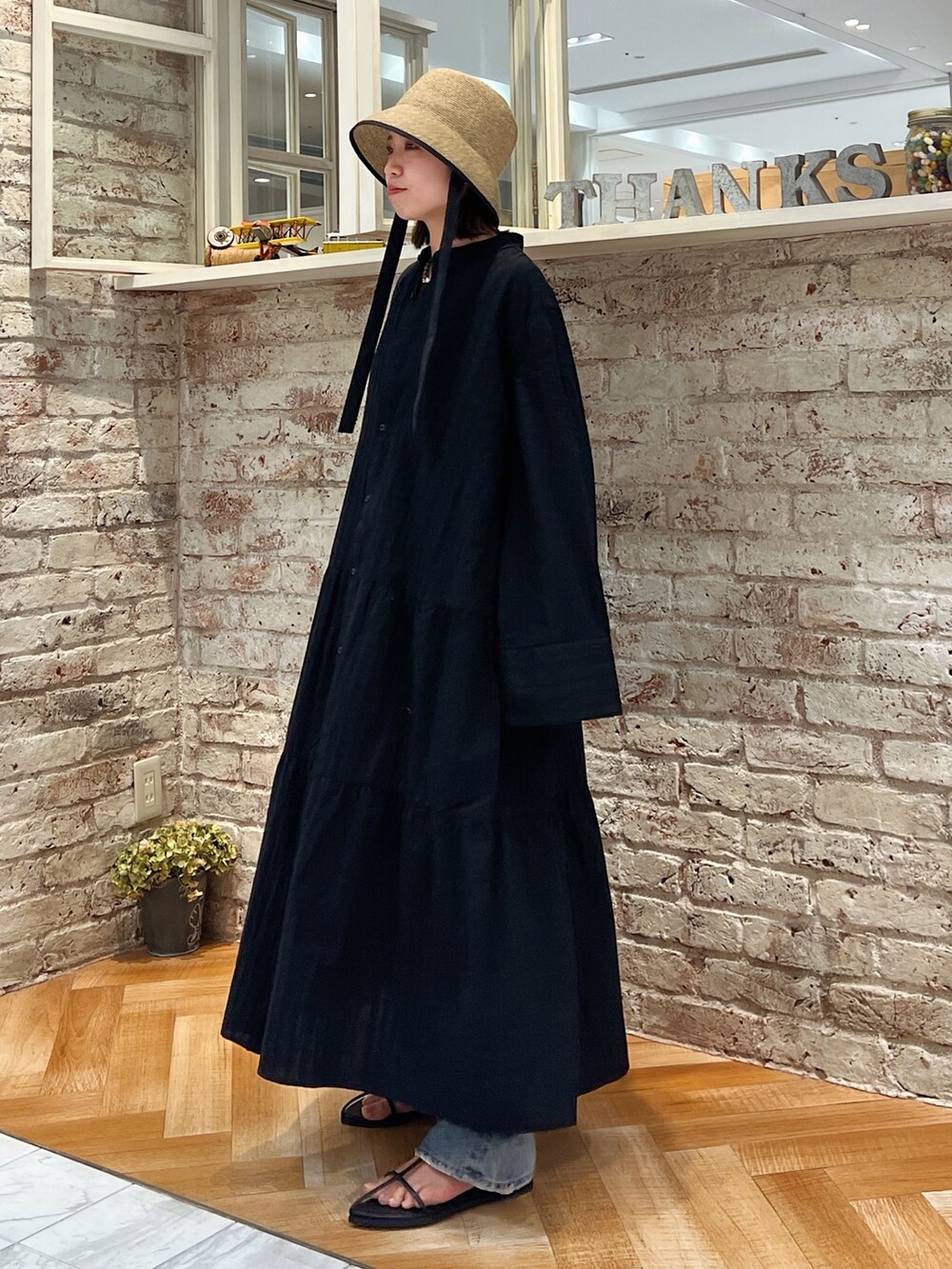 ブルー系のデニムパンツ、ブラック系のサンダル、ブラック系のワンピースを着用したレディースの春コーディネートの3枚目の写真