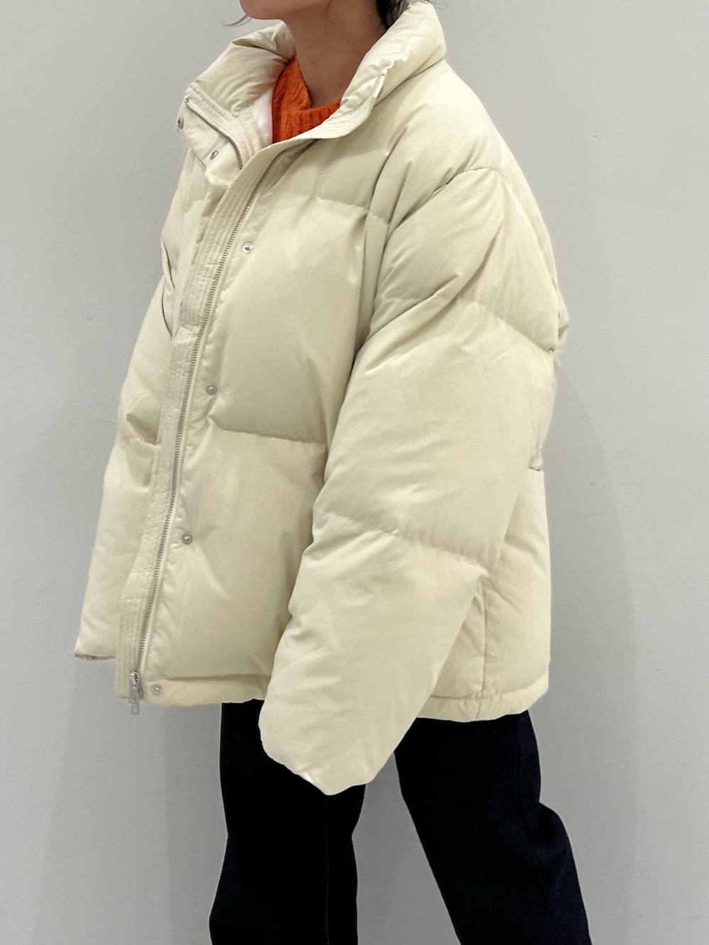 オレンジ系のニット/セーター、ブルー系のデニムパンツ、ホワイト系のダウンジャケット/コートを着用したレディースの秋コーディネートの6枚目の写真