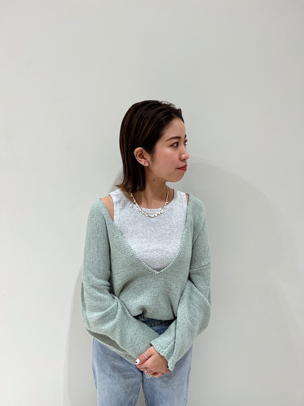 ブルー系のデニムパンツ、イエロー系のパンプス、グリーン系のニット/セーターを着用したレディースの冬コーディネートの9枚目の写真