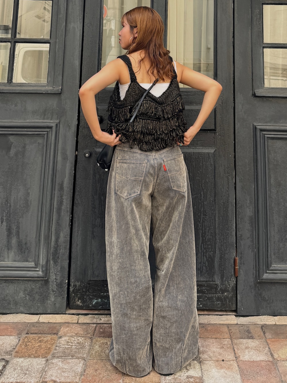 ベージュ系のデニムパンツ、ブラック系のニット/セーター、ベージュ系のスリッポンを着用したレディースの秋コーディネートの4枚目の写真