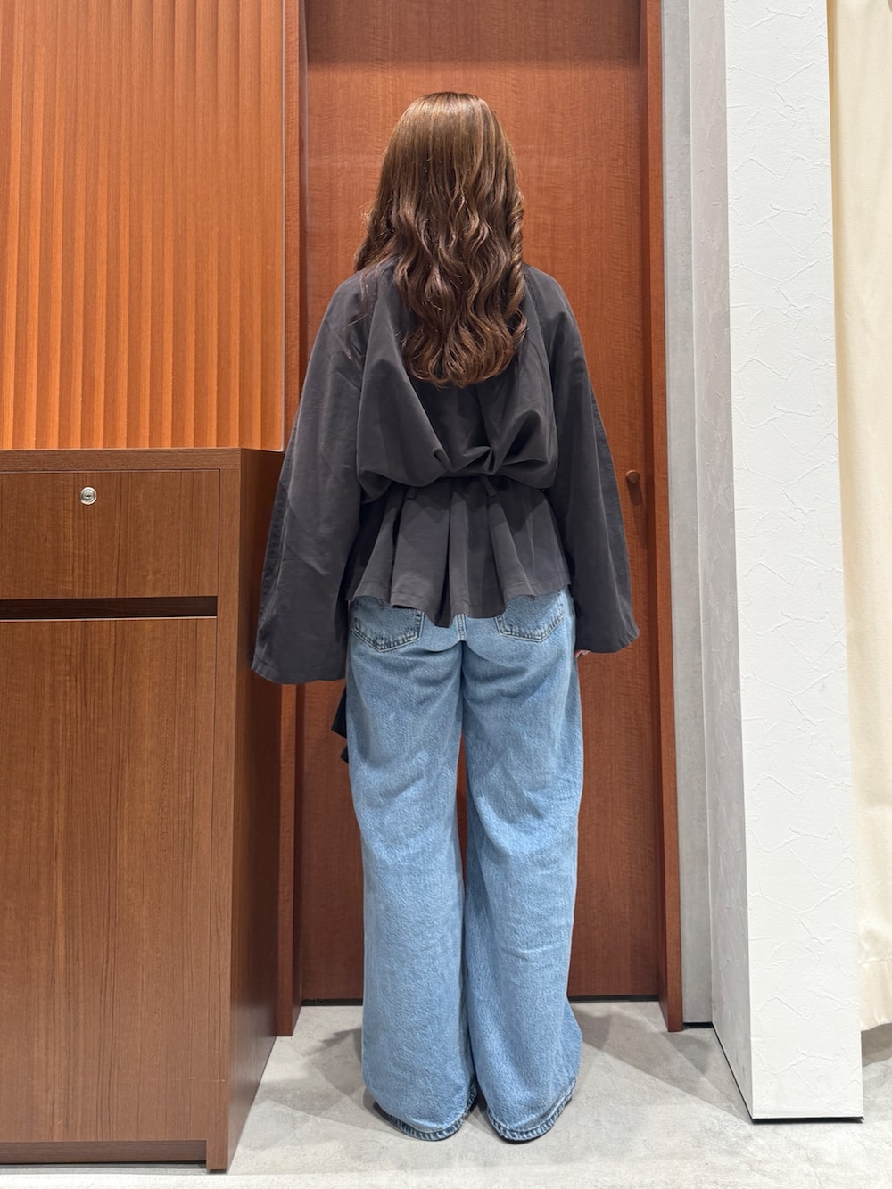 グレー系のトレンチコート、ブルー系のデニムパンツ、シルバー系のネックレスを着用したレディースの秋コーディネートの4枚目の写真