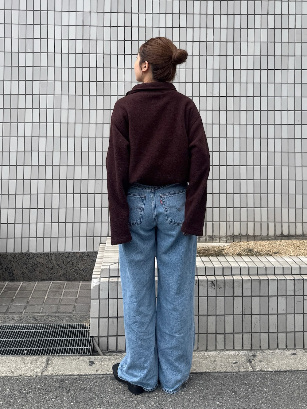 ブラウン系のパーカー、ブルー系のデニムパンツ、ブラック系のサンダルを着用したレディースの秋コーディネートの3枚目の写真