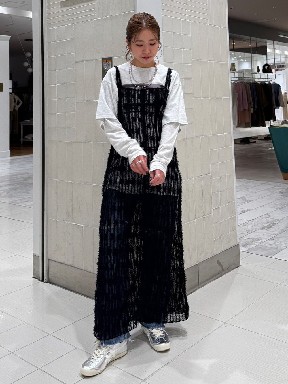 ブラック系のワンピース、グレー系のTシャツ/カットソー、ブルー系のデニムパンツを着用したレディースの春コーディネートの2枚目の写真