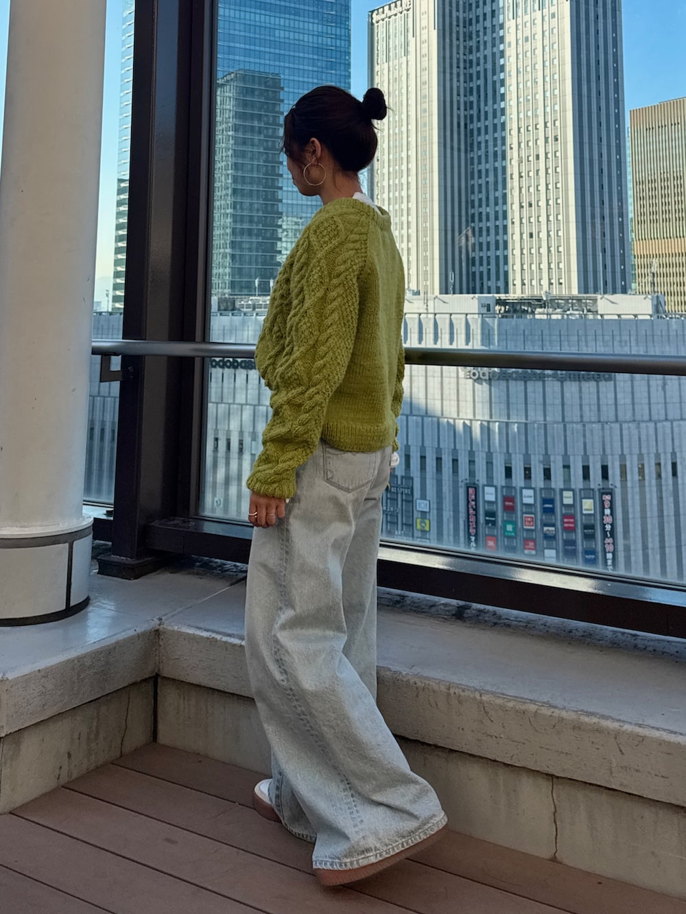 グリーン系のニット/セーター、ホワイト系のTシャツ/カットソー、ブルー系のデニムパンツを着用したレディースの冬コーディネートの3枚目の写真