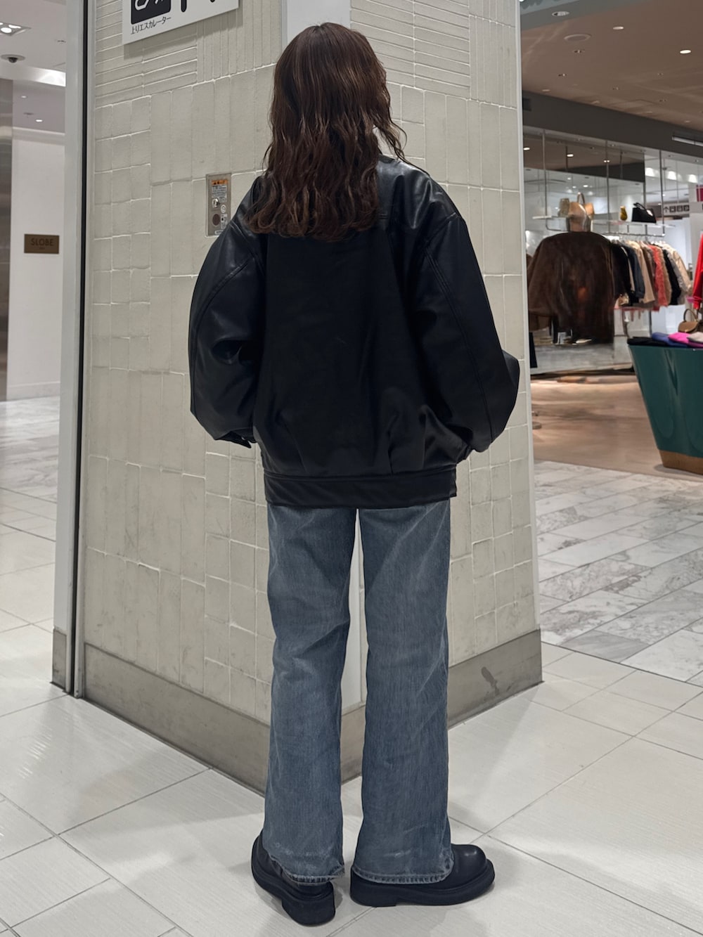 ブルー系のデニムパンツ、ブラック系のブルゾン、イエロー系のニット/セーターを着用したレディースの冬コーディネートの3枚目の写真