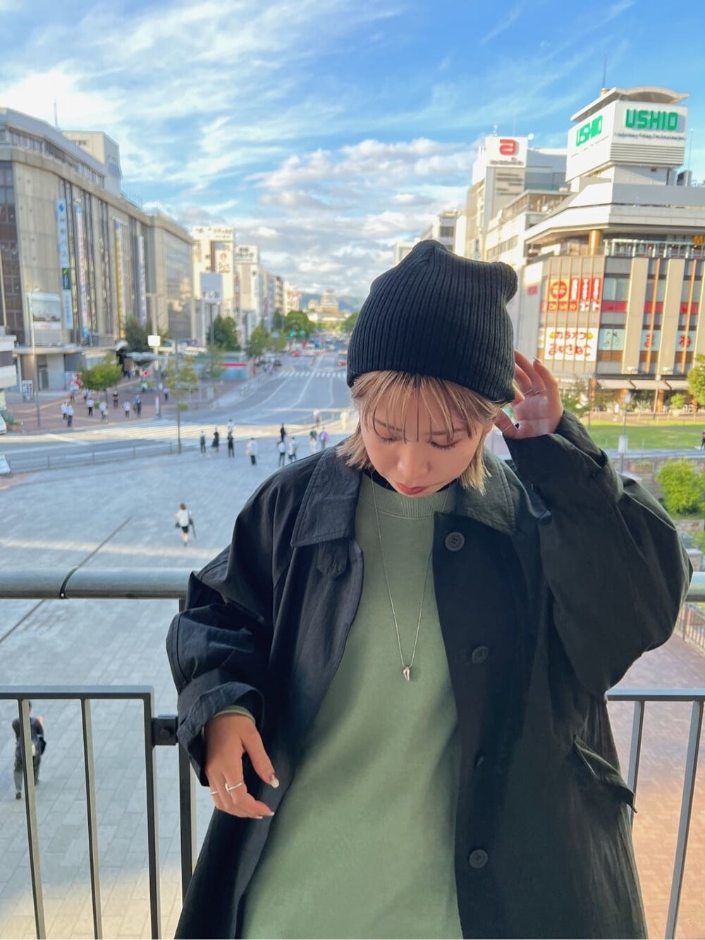 ブラック系のステンカラーコート、グリーン系のワンピース、ブラック系のブーツを着用したレディースの秋コーディネートの9枚目の写真