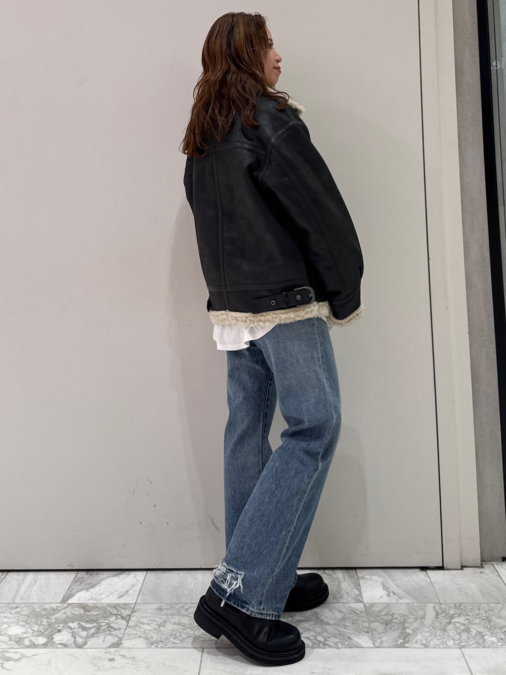 ブラック系のニット/セーター、ホワイト系のTシャツ/カットソー、ブラック系のブーツを着用したレディースの冬コーディネートの3枚目の写真