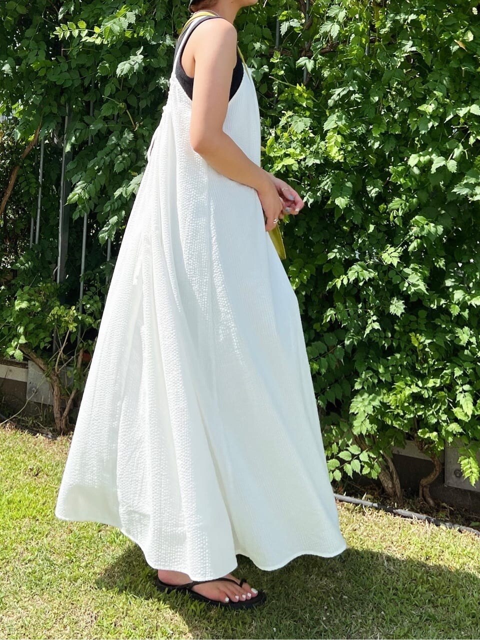 ブラック系のサンダル、ホワイト系のワンピース、ブラック系のタンクトップを着用したレディースの夏コーディネートの3枚目の写真