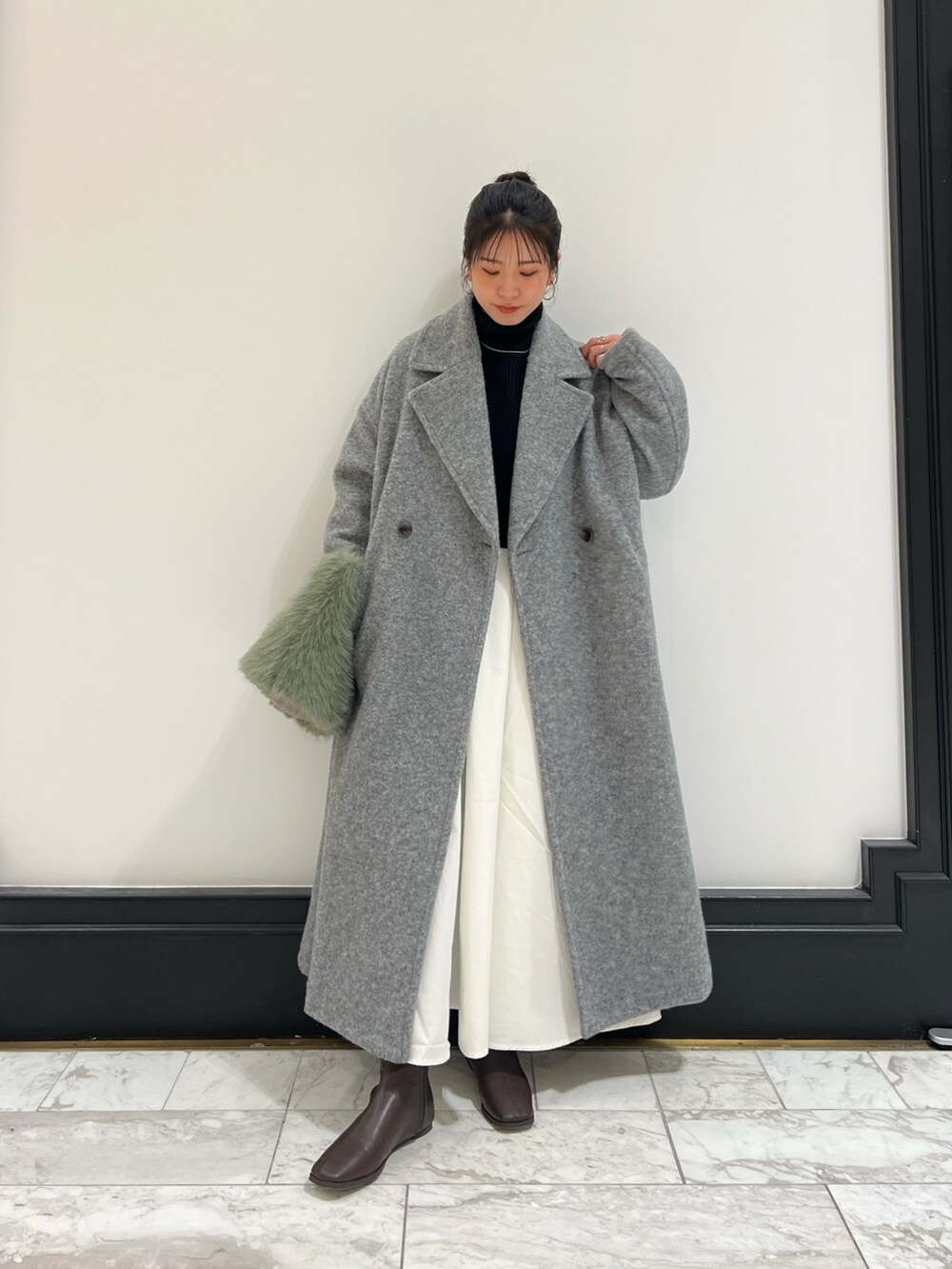 ブラウン系のブーツ、ブラック系のワンピース、グレー系のチェスターコートを着用したレディースの冬コーディネートの6枚目の写真