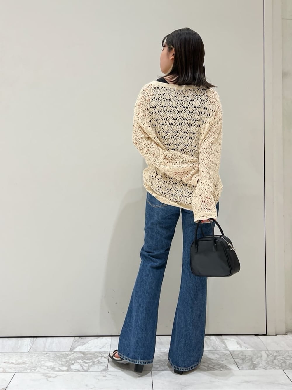 ブラック系のサンダル、ブラック系のハンドバッグ、ブルー系のデニムパンツを着用したレディースの春コーディネートの4枚目の写真