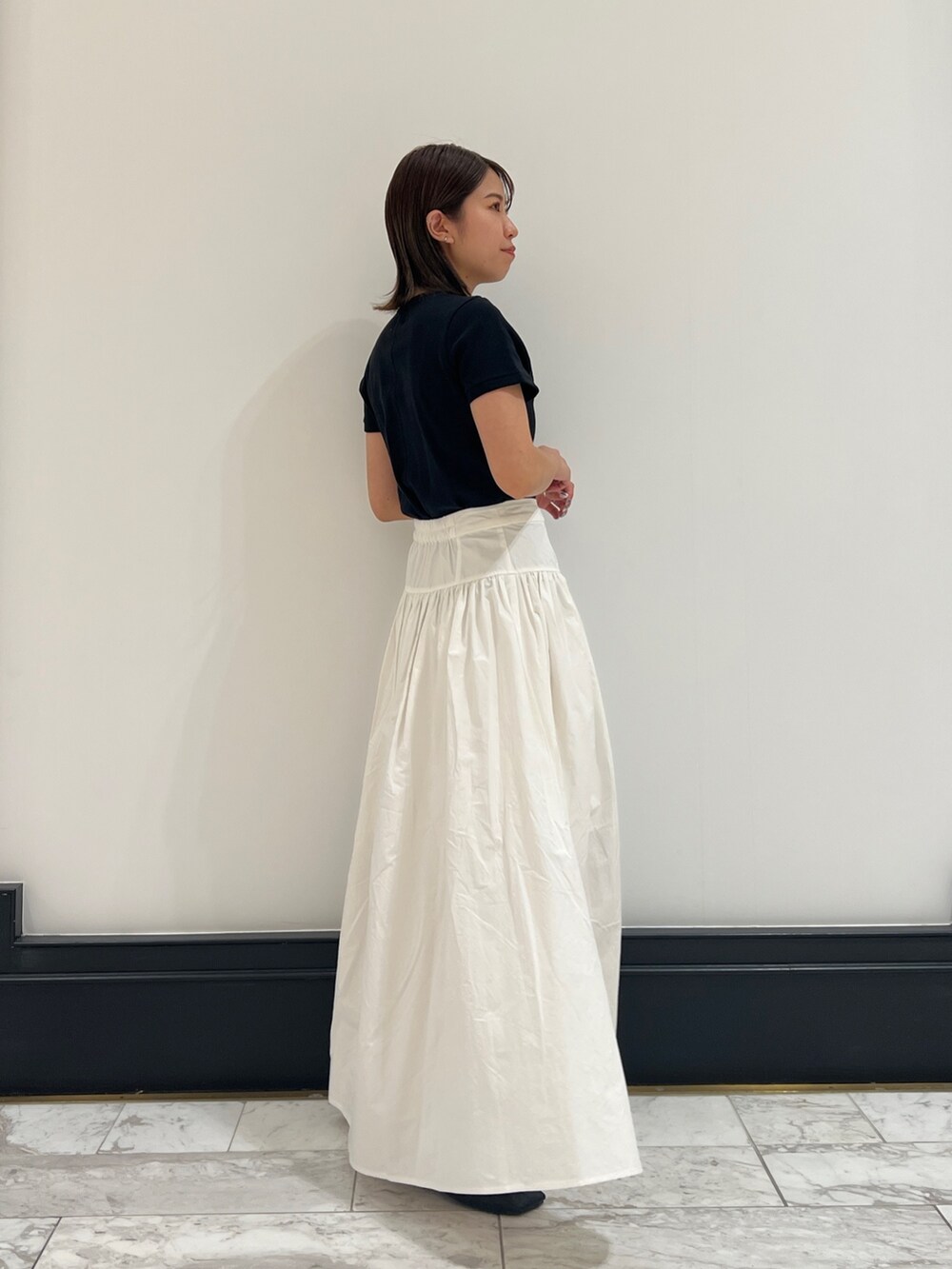 ホワイト系のスカート、ブラック系のTシャツ/カットソー、ブラック系のパンプスを着用したレディースの春コーディネートの2枚目の写真