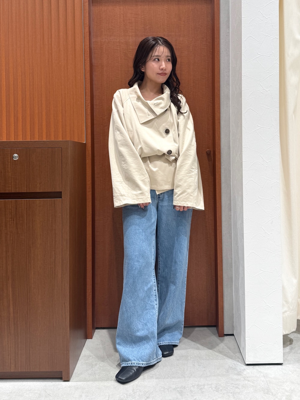 ベージュ系のトレンチコート、ブルー系のデニムパンツ、ブラック系のサンダルを着用したレディースの秋コーディネートの5枚目の写真