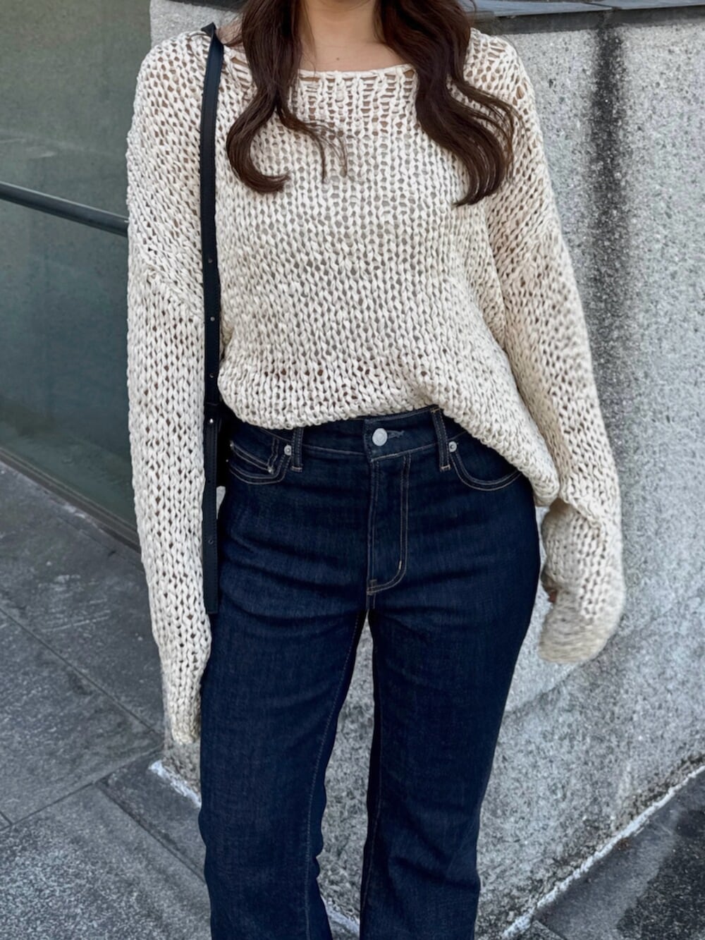 ブラック系のハンドバッグ、ブルー系のデニムパンツ、ブラック系のパンプスを着用したレディースの秋コーディネートの7枚目の写真