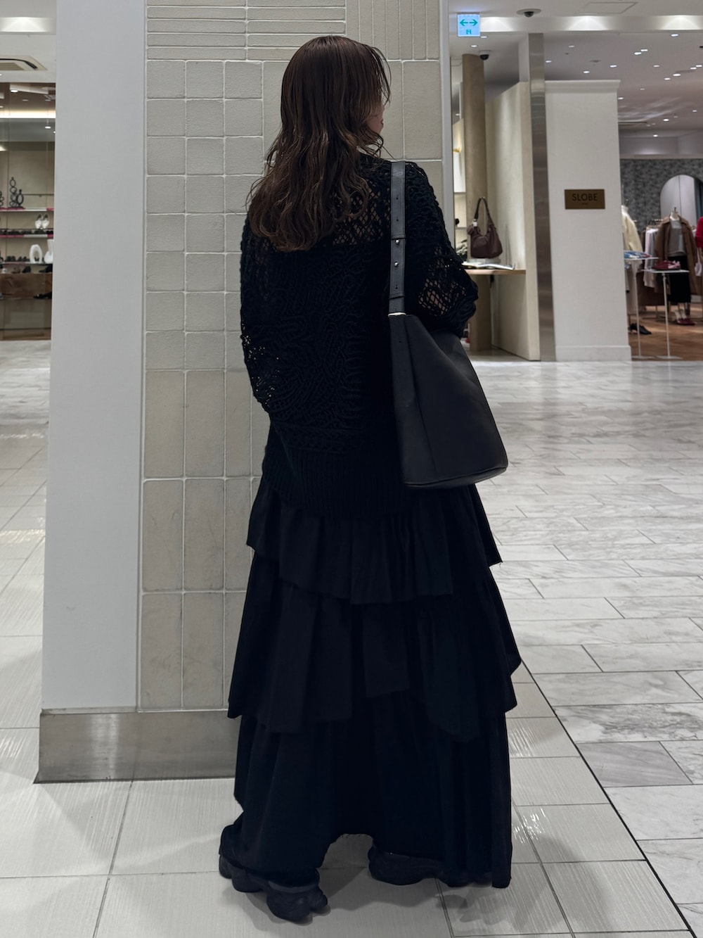 ブラック系のスカート、ブラック系のニット/セーター、ブラック系のショルダーバッグを着用したレディースの冬コーディネートの2枚目の写真