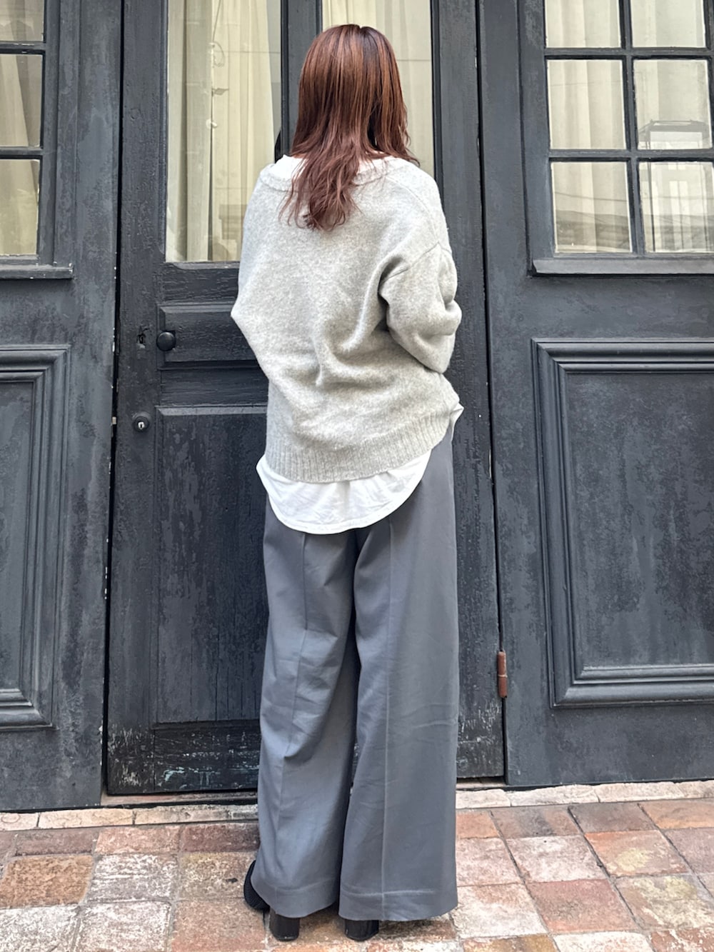 グレー系のニット/セーター、ホワイト系のTシャツ/カットソー、グレー系のその他パンツを着用したレディースの冬コーディネートの4枚目の写真