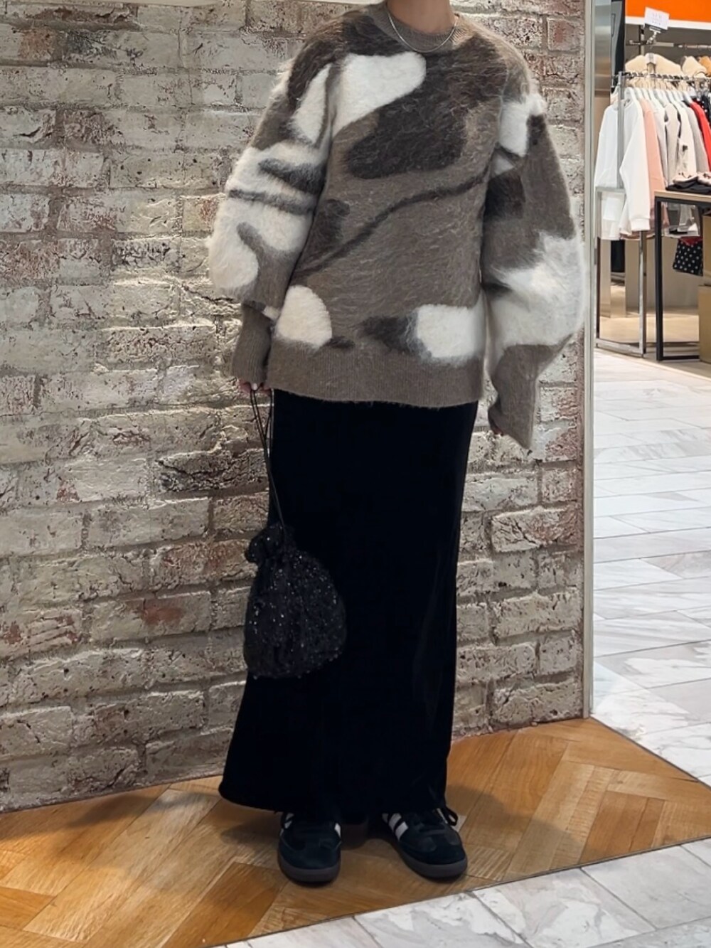 ブラック系のスカート、ブラック系のハンドバッグ、ベージュ系のニット/セーターを着用したレディースの秋コーディネートの10枚目の写真