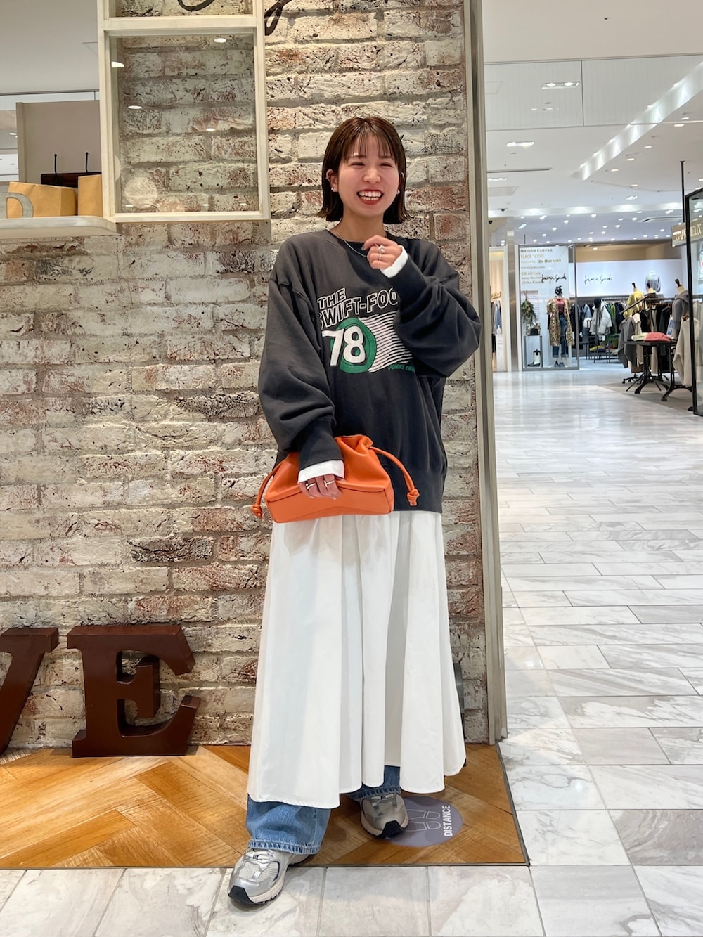 グレー系のスウェット、ブラック系のワンピース、ブルー系のデニムパンツを着用したレディースの冬コーディネートの5枚目の写真