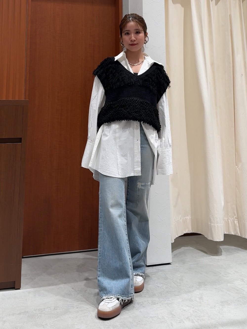 ブラック系のベスト、ホワイト系のシャツ/ブラウス、ブルー系のデニムパンツを着用したレディースの春コーディネートの7枚目の写真