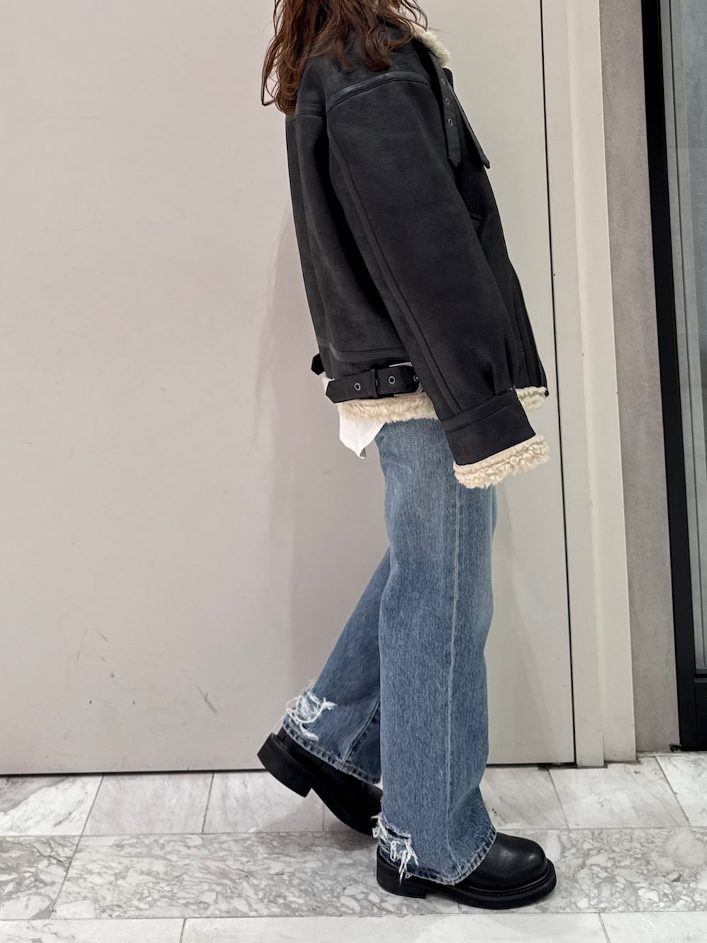 ブラック系のニット/セーター、ホワイト系のTシャツ/カットソー、ブラック系のブーツを着用したレディースの冬コーディネートの5枚目の写真