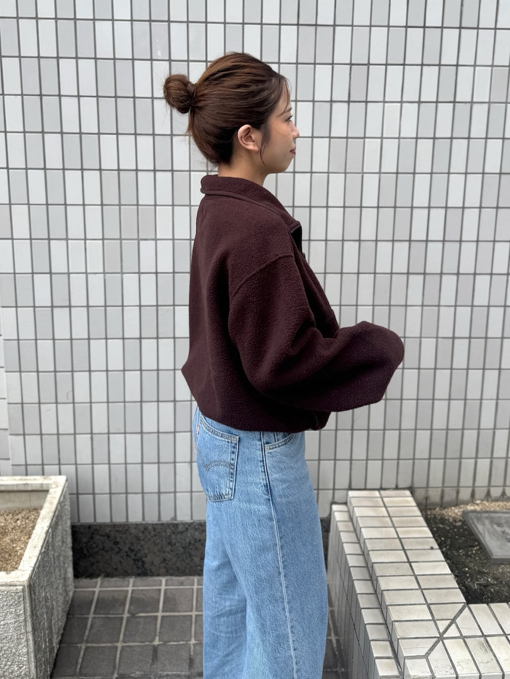 ブラウン系のパーカー、ブルー系のデニムパンツ、ブラック系のサンダルを着用したレディースの秋コーディネートの8枚目の写真