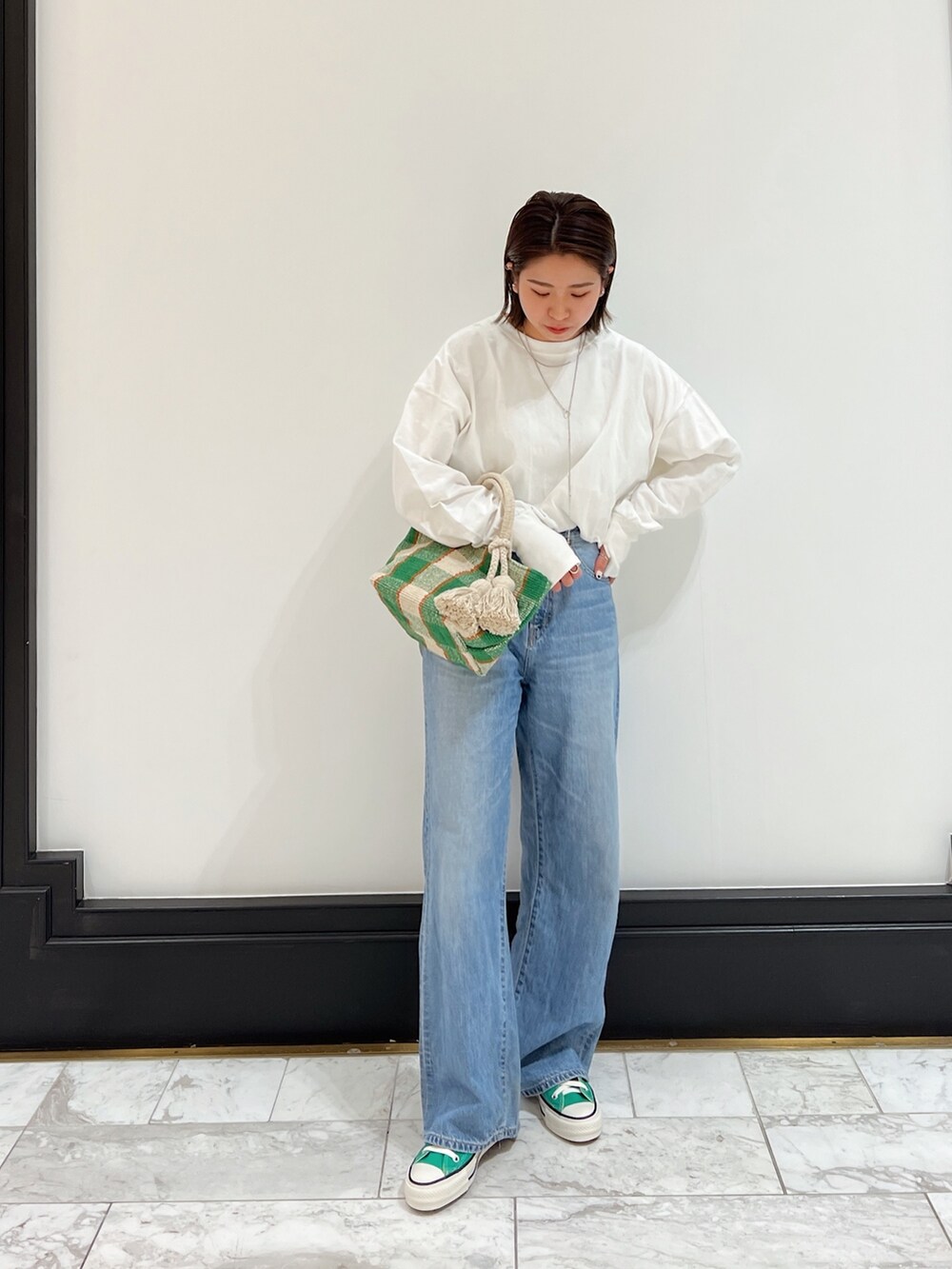ブルー系のデニムパンツ、グリーン系のスニーカーを着用したレディースの春コーディネートの2枚目の写真