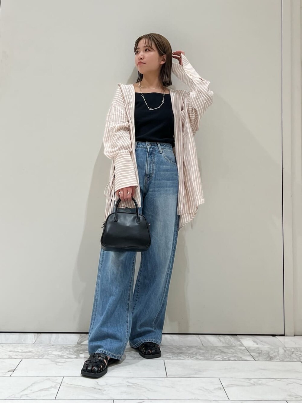 ブラック系のサンダル、ピンク系のシャツ/ブラウス、ブラック系のハンドバッグを着用したレディースの春コーディネートの2枚目の写真