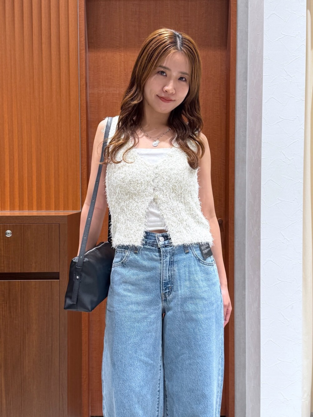 ブルー系のデニムパンツ、ホワイト系のベスト、ブラック系のハンドバッグを着用したレディースの夏コーディネートの10枚目の写真